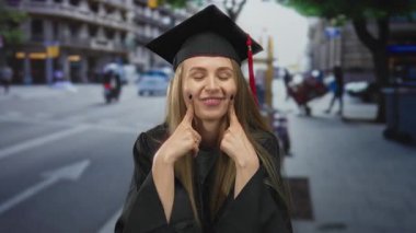 Yoğun bir şehir caddesinde kep ve cübbe içinde gülümseyen mezun bir kadın, arka planda hareketli bir şehir hayatı ile neşe ve başarıyı somutlaştırıyor.