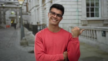 Gözlüklü gülümseyen genç adam, şehir sokaklarında olumlu ve modern bir şehir yaşam tarzını sıradan bir ortamda somutlaştırıyor..
