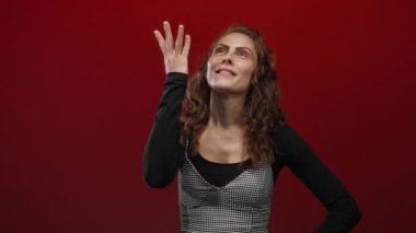 Dudaklarını birbirine kenetleyen kadın, canlı kırmızı bir arkaplan karşısında duruyor. Gizliliği ve mahremiyeti sembolize ediyor..