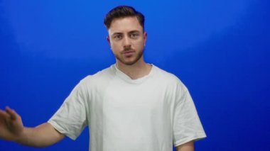 Sakallı genç adam canlı mavi arka plana el sallıyor. Bu da ayrı bir ortamda selamlama ya da veda jesti anlamına geliyor.