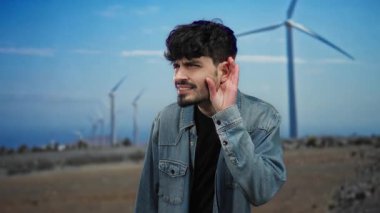 Bir tarlada el pençe divan duran genç adam mavi gökyüzünün altında yel değirmenlerinin önünde duruyor. Kot ceket giymiş, doğa enerjisini ve merakını gözler önüne seriyor..