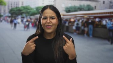 Latin kökenli genç, açık hava pazarında bir kadın sokakta parmak hareketi gösteriyor..