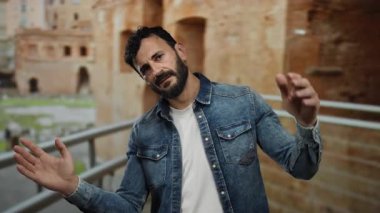 Eski Roma 'da sakallı İspanyol bir adam. Kot ceket giyiyor. Tarihi tuğla mimarisine karşı.
