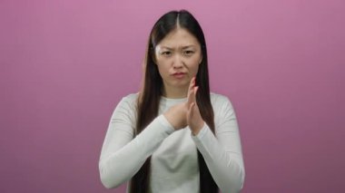 Kapalı yumruklarla canlı pembe bir arka plana karşı kararlılığını ifade eden bir kadın izole edilmiş bir stüdyo ortamında güç ve direnç gösteriyor..