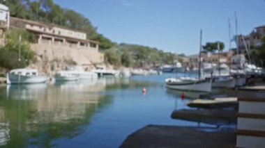 Mallorca 'daki Cala figera limanının bulanık görüntüsü, berrak bir gökyüzü altında sönmüş tekneleri ve manzaralı limanı gösteriyor, sakin bir deniz atmosferini yakalıyor..