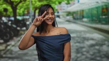 İspanyol kadın yeşil ağaçların altında bir tebessümle şehir sokaklarında zafer jesti yapıyor..