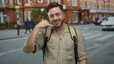 Sokakta sakallı ve sırt çantalı genç bir adam, canlı bir şehir ortamında turist enerjisi somutlaştırıyor tuğla binalar ve bulanık yaya geçmişi ile.