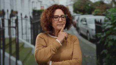 Şehir caddesinde düşünen bir kadın, şehir arka planında orta yaşlı moda açık havada düşünceli bir yansıma olduğunu gösteriyor..