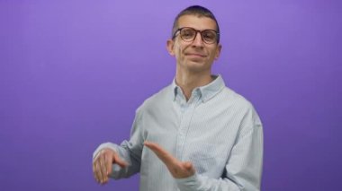 Gözlüklü bir adam mor bir arkaplanı işaret ediyor, izole edilmiş ve gülümseyen, konsept ya da fikir sunan, kendine güvenen bir duruşu olan çizgili gömlek giyen, profesyonel tavır sergiliyor..