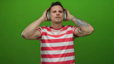 Kolunda dövmeleri olan, çizgili tişörtlü, kulaklık takan bir adam, kafa karışıklığı ve düşünceliliğini ifade ediyor..