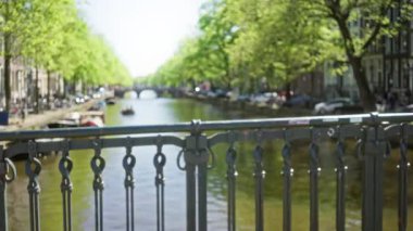 Amsterdam 'da çözünmüş bir korkuluk, parlak bir yeşillik ve huzurlu bir şehir atmosferini taşıyan sakin bir su üzerinde bulanık bir manzara..