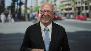 İşletme kıdemli bir adam kalabalık bir caddede gülümsüyor, açık havada profesyonel ve neşeli bir tavır sergiliyor..