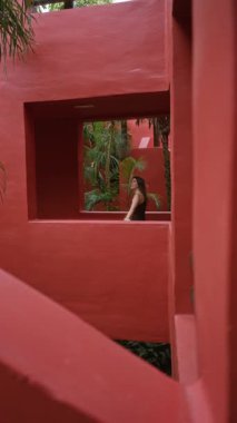 Zengin palmiye ağaçlarıyla çevrili canlı kırmızı mimarisiyle tropikal lüks otellerden hoşlanan bir kadın sakin ve egzotik bir atmosfer yaratıyor..