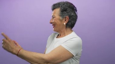 Gri saçlı, gülümseyen ve parlak mor arkaplanına işaret eden son sınıf öğrencisi bir kadın neşeli ve çekici bir ifade sergiliyor..