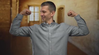 Bir adam açık hava üniversitesinde tarihi mimari ile kaslarını esnetiyor, gelişigüzel bir ortamda güven ve güç gösterisi yapıyor..