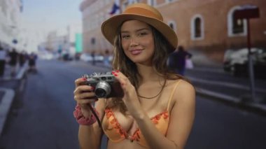 Elinde kamera olan İspanyol bir kadın, sokak manzaralarını inceliyor, genç bir turist olarak yaptığı seyahatler sırasında kentsel anları yakalıyor..