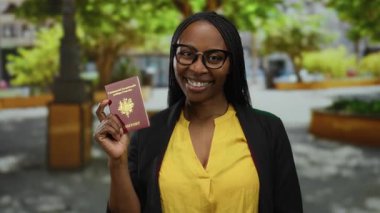 Park ortamında Fransız pasaportu taşıyan, kendine güvenen, gözlük takan, günlük kıyafet giyen seyahat ve kimlik belgelerini temsil eden bir kadın..