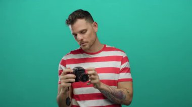 Dövme kamerası olan genç adam, izole edilmiş yeşil arka plana karşı endişeli görünüyor..