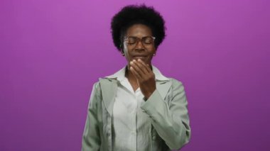 Gülümseyen ve ağzını yalıtılmış pembe bir arka planda kapatan bir kadın neşeli bir ifadeyle dinamik ve canlı bir ortamda neşe ve güveni vurguluyor..