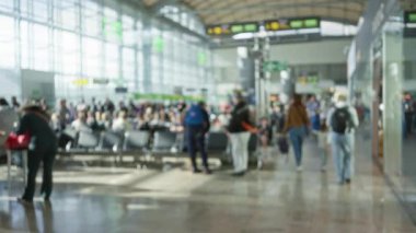 Havaalanı terminali bulanık şekiller ve parlak güneş ışığıyla dolup taşıyor. Geniş pencerelerden süzülerek seyahat ve hareketin dinamik atmosferini yakalıyor..