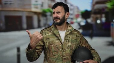 Askeri üniformalı İspanyol bir adam şehir sokaklarında miğfer takıp şehir senaryosunu sergiliyor..