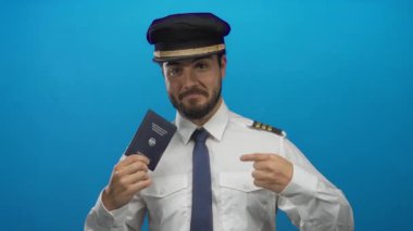 Üniformalı genç sakallı pilot mavi arka planda Alman pasaportuyla gülümsüyor, kendinden emin ve profesyonel bir tavır sergiliyor..