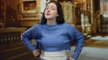 Katolik kilisesinde kendine güvenen bir kadın, esmer saçlı, mavi kazaklı, dinsel mimari ortamına ışıldayan bir güzellik ve zarafet katıyor..