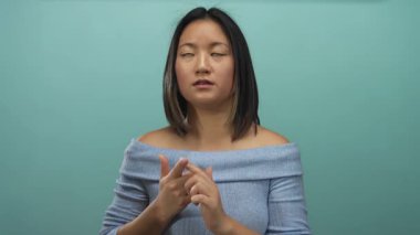 Tecrit edilmiş yeşil duvarın üzerinde genç bir kadın. Düşünceli görünüyor. Parmakları sayarken anlamlı bir yüzü var..