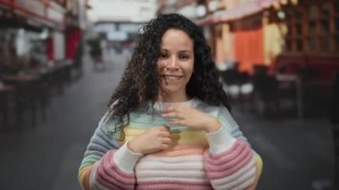 Açık hava restoranındaki terasta kutlama yapan İspanyol kadın renkli süveter ve kahve arkaplanı giyiyor..