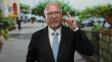 Takım elbiseli kıdemli bir adam hareketli bir caddenin tepesinde, açık hava iş ortamında etkileyici bir jest sergiliyor..