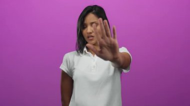 Beyaz gömlekli kadın, canlı pembe arka plana el kaldırarak jesti durduruyor. İnkâr ediyor ya da tek bir ortamda reddediyor..