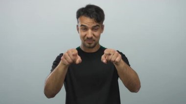 Genç İspanyol bir adam, izole edilmiş beyaz arka plana karşı davetkar ve kendinden emin bir ruh halini vurgulayarak işaret ediyor.