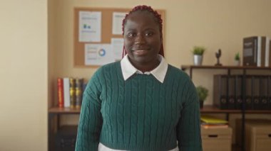 Ofiste gülümseyen bir kadın, iş ortamında kendine güvenini ve pozitifliğini gösteriyor, neşeli ifadesini ve profesyonel kıyafetini vurguluyor..