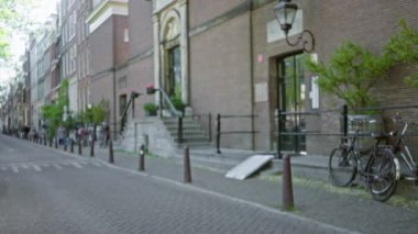 Kentsel bir Avrupa ortamında tuğla binalar ve bisikletlerle kaplı bulanık bir sokak manzarası, dağılmış mimari ve şehir havasını sakin bir günde biraz yeşillikle sergilemek.