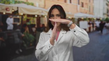 Beyaz önlüklü bir kadın, şehir manzarası ve açık hava yemek atmosferiyle çevrili sokak terası kahvecisinde mola veriyor. Şehir ortamını yakalıyor..