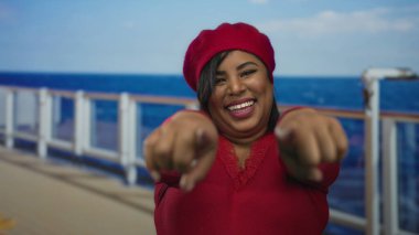 Kırmızılı kadın deniz manzaralı yolcu gemisinde gülümsüyor ve deniz kenarında neşeli bir tatil ruhu sergiliyor..