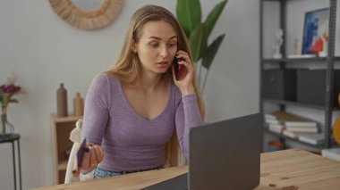 Akıllı telefondan konuşan, evinde dizüstü bilgisayar kullanan, mor gömlek giyen oturma odasında oturan uzaktan kumandalı bir kadın..