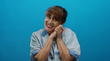 Mavi arka planda gülümseyen İspanyol üniformalı son sınıf öğrencisi kadın, temizlik işinde mutluluk ve memnuniyetini ifade ediyor, profesyonel bir portre için izole edilmiş..