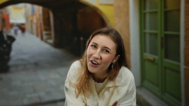 Arka planda renkli binalar olan büyüleyici bir şehir caddesinde gülümseyen bir kadın, şehir dışı hayatının özünü neşe ve duyguyla yakalıyor..