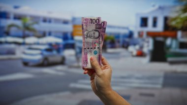 Şehirdeki sokak sergilenen yatırım temasında el ele tutuşan Filipin pesoları bulanık şehir arka planında para ve iş dinamiğini canlı açık hava ortamında vurguluyor.