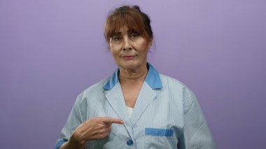 İspanyol temizlikçi üniformalı son sınıf öğrencisi kadın, izole bir ortamda profesyonellik ve dostluk saçan mor duvar altyapısı ile onaylıyor..