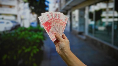 Bir şehir caddesinde el ele tutuşan İzlanda Krona banknotları, bir kentsel ortamda iş, yatırım ve döviz potansiyelini sembolize ediyor.