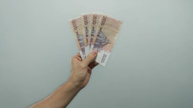 İzlanda Krona banknotları tutan adam izole edilmiş beyaz bir arkaplan karşısında, finansal başarı ve para yönetimi minimalist bir ortamda sergileniyor.