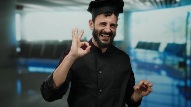 İspanyol şef sakallı. Havaalanı Terminali 1 'de beklenmedik bir seyahat ayarında neşeli ve kendine güvenen bir jest yapıyor..