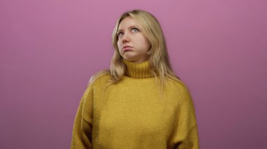 Sarı kazaklı kadın pembe arka planda dalgın görünüyor. Sarı saçlı ve sıradan giyinmiş. Gençlik tarzını ve moda ifadesini temsil ediyor..