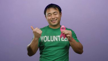 Mor arka planda pembe kurdele tutan Asyalı gönüllü gönüllü göğüs kanseri farkındalığını destekliyor..