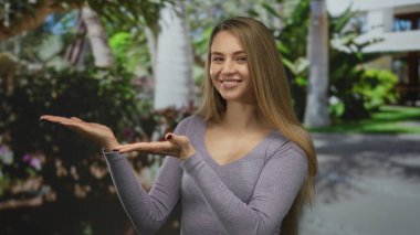 Bereketli yeşil parkta sunan genç bir kadın güneşli bir günde açık havada, hayat dolu gençlik enerjisini ve neşesini somutlaştırıyor..