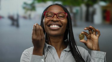 Elinde kripto para tutan kadın açık havada gülümsüyor şehir sokaklarında coşku ve modern teknolojiyi yansıtıyor.