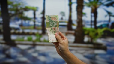 Bir şehir caddesinde el ele tutuşan Hong Kong doları, kentsel bir ortamda mali yatırımı ve döviz takasını simgeliyor..