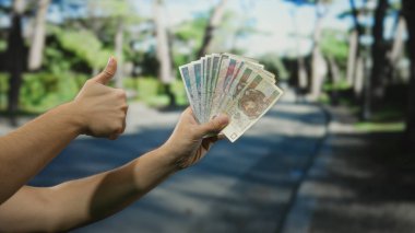 Bir şehir caddesinde, olumlu bir jest ile, açık bir şehir ortamında finansal başarı ve pozitiflik sergileyen, Polonya 'lı banknotlar tutan bir adam..